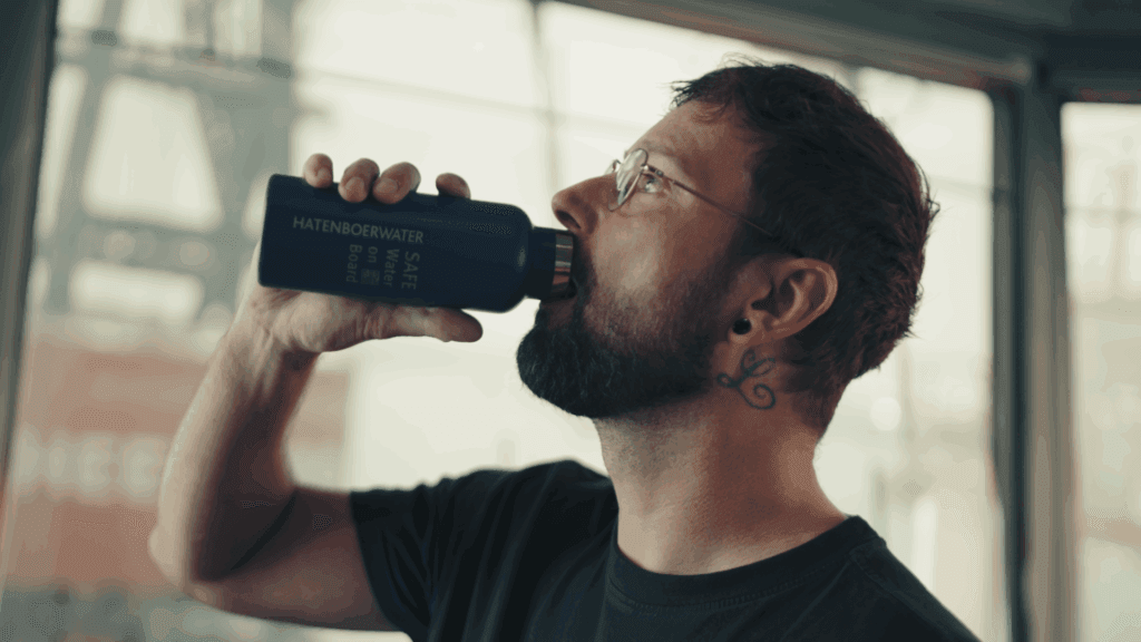 a sailor drinking from a reusable water bottle, contributing to UN SDG 12.